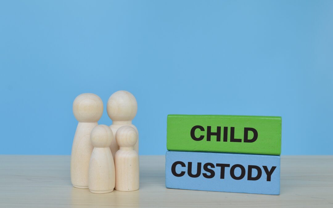 Two tall and two small wooden doll figures representing a family standing next to wooden blocks with the phrase “Child Custody.”